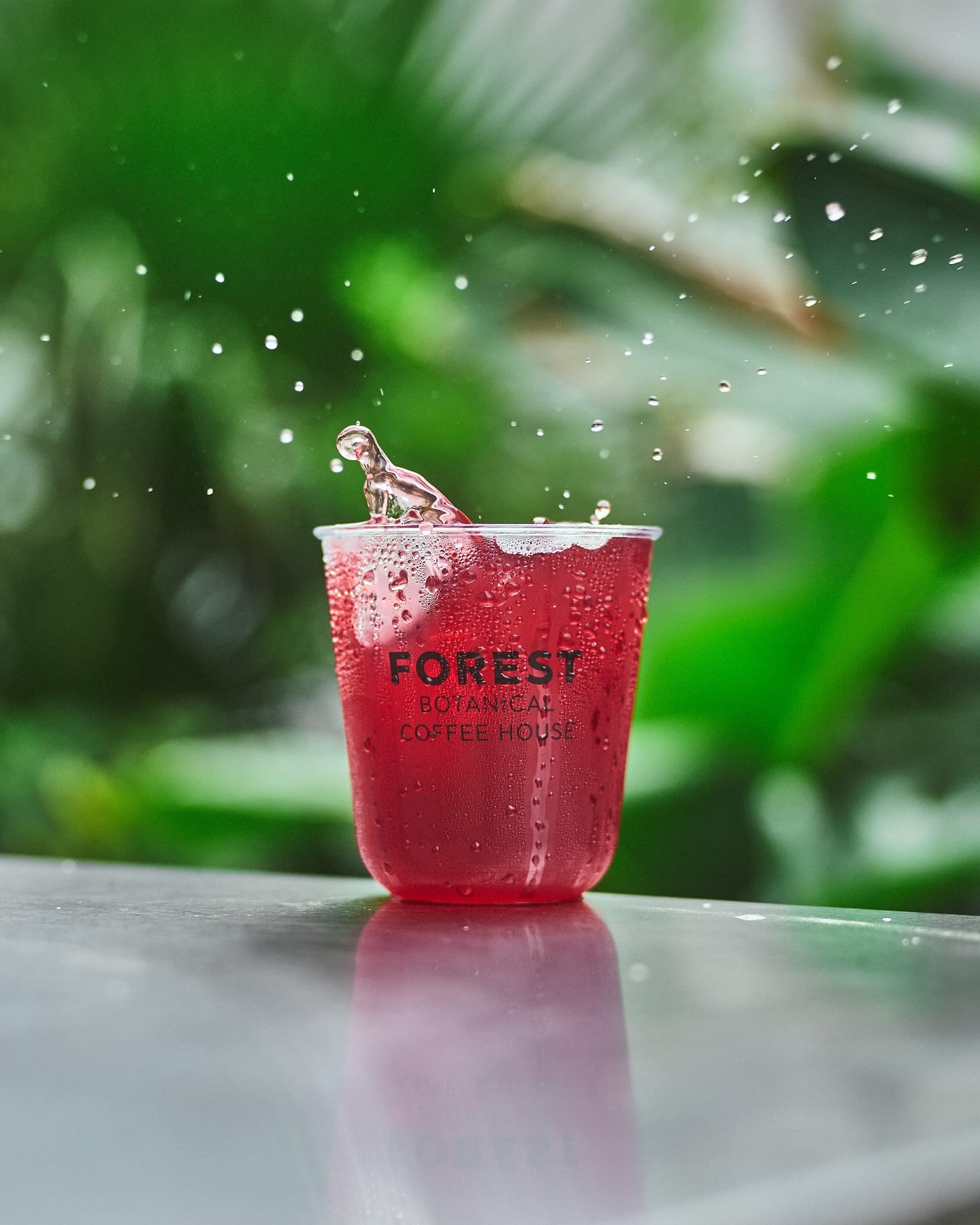 The pink forest ice tea splashing on a steel table